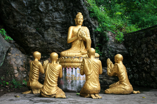 Gold sitting buddha surrounded by monk students