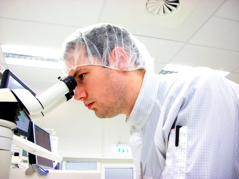 The men looks in stereomicroscope eyepieces