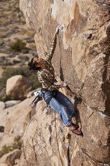 Female climber clinging to a cliff.