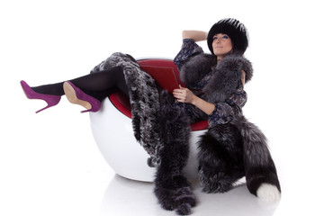 Young woman in fur with laptop sit on armchair