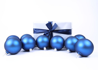Blue matt christmas balls and a gift in red wrapping on white