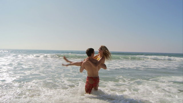 Young couple playing in ocean