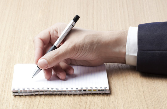 main et stylo &eacute;crivant sur bloc notes calepin