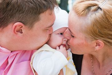 Mother and father kissing baby's cheek