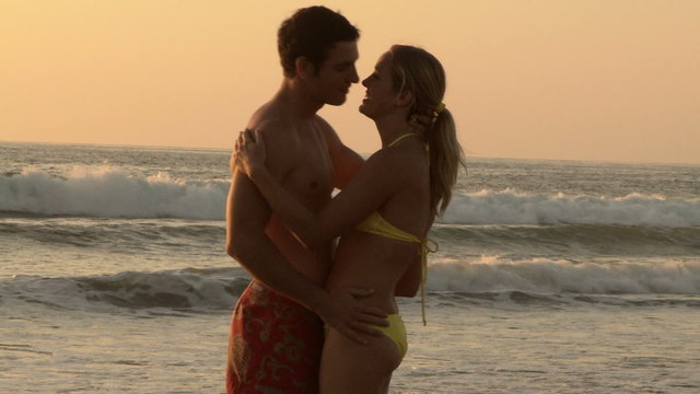 Young couple kissing on beach at sunset