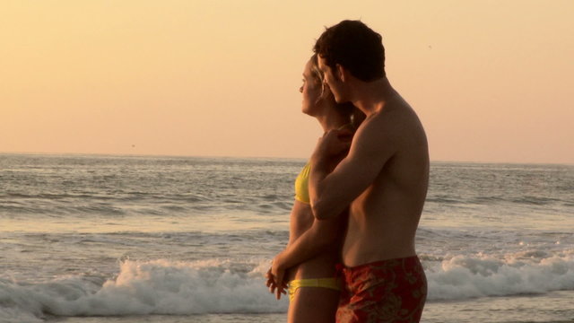 Young couple kissing on beach at sunset