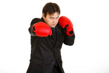 Punching furious young businessman with boxing gloves