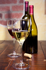 Glasses of white and red  wine and bottles on a table