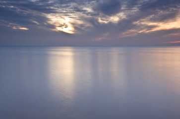 Naklejka premium Beautiful fiery glow sunset reflected in smooth sea