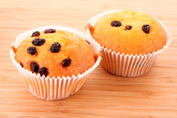 Muffins with raisins on wooden surface