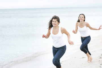 two young happy women running on beach