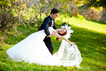 dancing wedding couple at a park on a sunny day