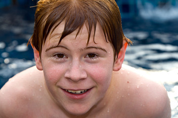 smiling and happy boy with red hair is swimming and relaxing