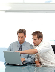 Two partners working together on a laptop sitting at a table