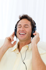 Happy man singing while listening to the music on the sofa