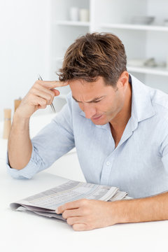 Concentrated Man Doing A Cryptic Crossword Sitting In His Kitche