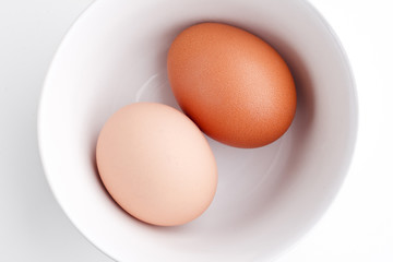 Two chicken eggs in a white bowl.