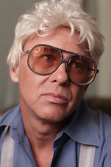 Headshot of a man wearing oversized glasses and looking away
