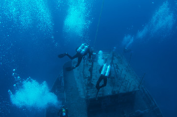 Scuba divers descending on a shipwreck.