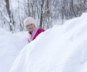 Fototapeta na wymiar Smiling child looking out from a large pile of snow