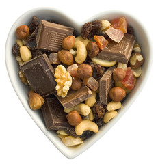 Chocolate, dried fruits and nuts in a heart shaped bowl.