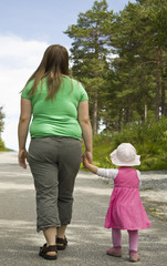 Obese mother and child walking on a forest path