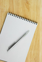 Pen and blank note pad on wooden background