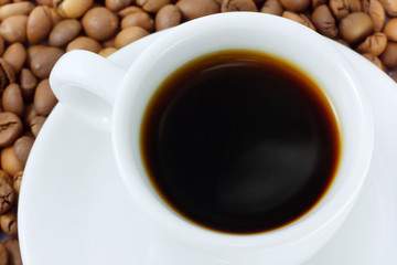Cup with beverage and coffee beans as background