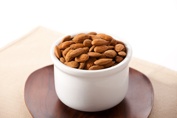 Almonds in a bowl sitting on a wooden plate