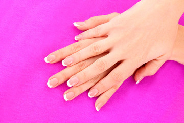 Beautiful woman hand with french manicure on pink background