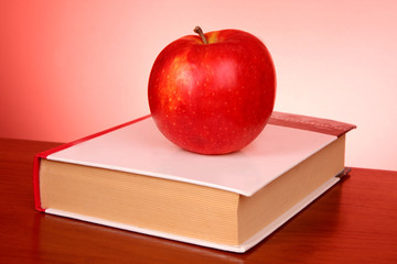 books and an apple on the red background