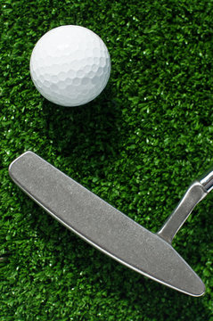 Golf ball and putter on green grass background