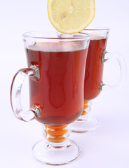 Two glasses of tea with lemon being put into one of them