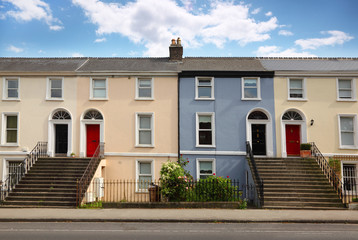 small three-story house stands beside road. doors, windows