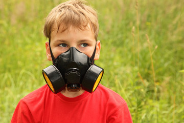 little boy in shirt with black respirator on face is in nature