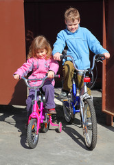 little brother and sister ride children's bicycles. girl in pink