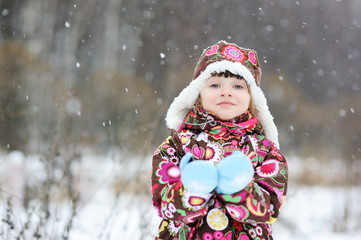 Adorable small girl cathches snowflakes