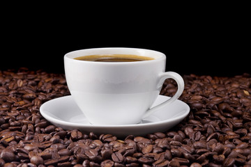ceramic cup of coffee and beans on black