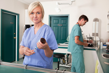 Nurse with syringe while doctor writing report