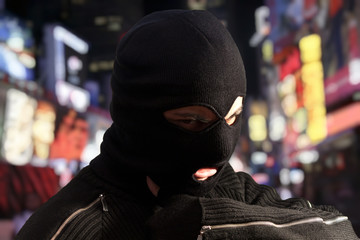 Thief wearing ski mask with city lights on the background