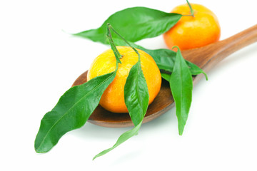 mandarin with green leaves on a wooden spoon isolated on white