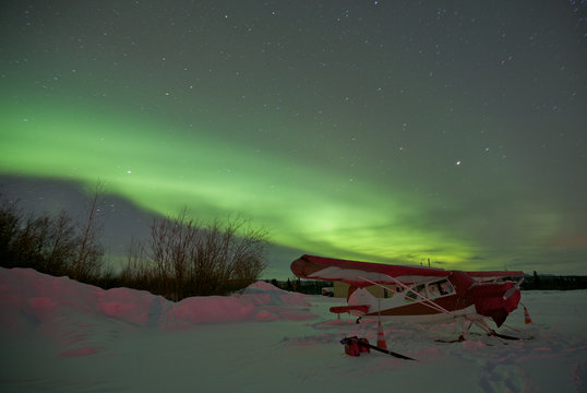 Airplane Parked in Snow Under Northern Lights