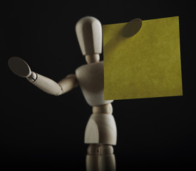 Wooden dool figure keeps yellow office sheet