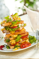 Skyscraper of toast with scrambled eggs tomatos and salat