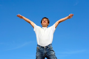 happy teenager jumping on blue sky background