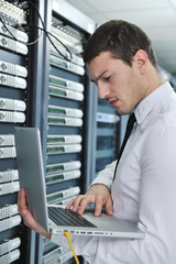 businessman with laptop in network server room