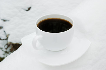 Cup of hot coffee on cold white snow