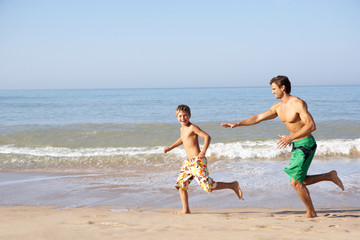 Fototapeta na wymiar Father chasing young boy on beach