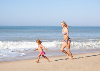 Fototapeta premium Mother chasing young girl on beach