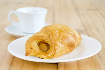 A cup of black coffee with Plate of sausage rolls